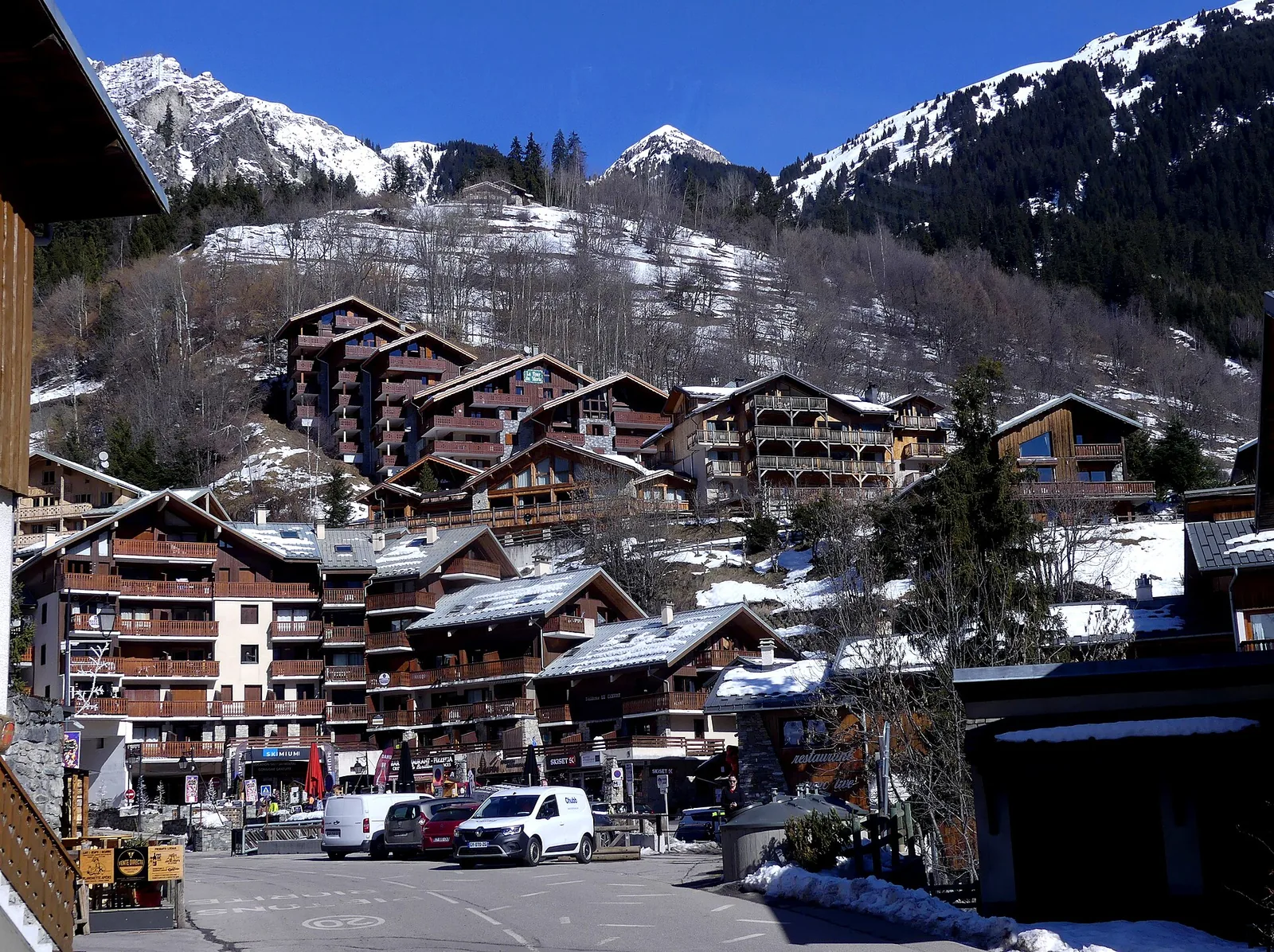 Snow-covered Champagny-en-Vanoise village below forested slopes in winter