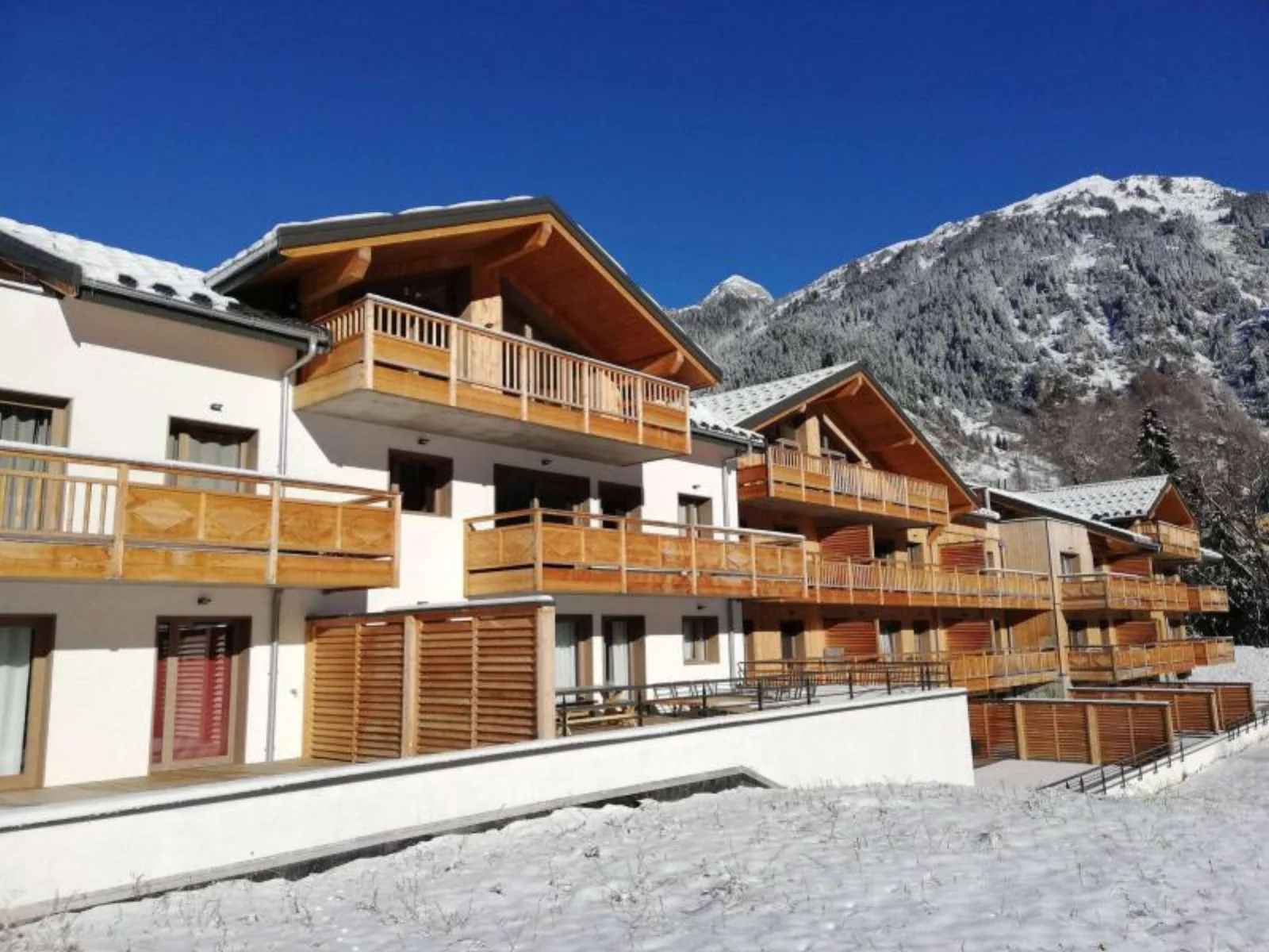 Les Terrasses de la Vanoise white-and-wood apartment residence against a snowy mountain slope